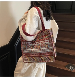 Detail of bohemian woven tote bag with colorful geometric patterns and red strap