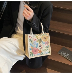 Detail der gewebten Tasche mit bunten Blumenmustern und Seilgriffen aus Baumwolle