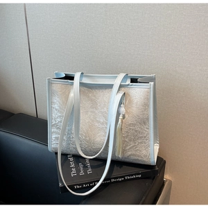 Detail of light blue tote bag featuring embossed floral leaf patterns and a tassel charm