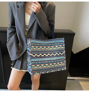 Detail of bohemian canvas tote bag with multi-color geometric patterns and blue handles