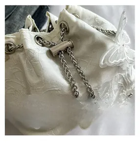 Detail of white lace bucket bag with 3D butterfly appliques and pearl chain tassels