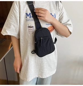 Gros plan du sac bandoulière en nylon noir avec sangle réglable et détails zippés