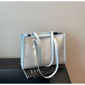 Detail of light blue jacquard tote bag with embossed feather texture and tassel