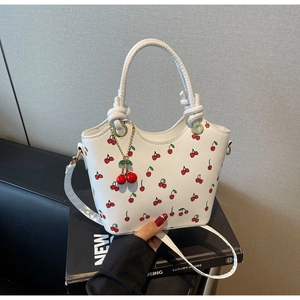 Détail d'un sac seau blanc à imprimé cerises avec charm et fine bandoulière