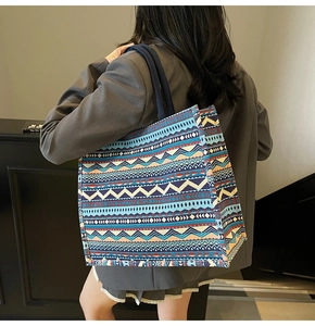 Close-up of bohemian geometric woven tote bag with colorful ethnic patterns and blue handle