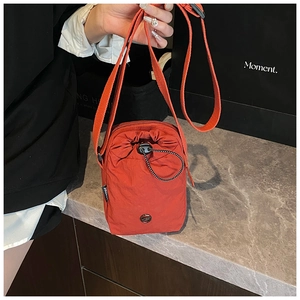 Detailed close-up of orange waterproof nylon crossbody bag with drawstring closure