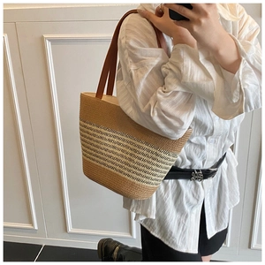 Detailed view of large straw tote with striped pattern and brown leather straps on model