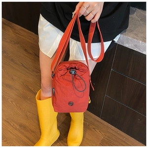 Close-up of red nylon drawstring crossbody bag with adjustable strap and logo detail