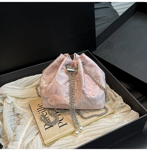 Detail of pink bucket bag with butterfly embroidery, silver chain, and pearl charms