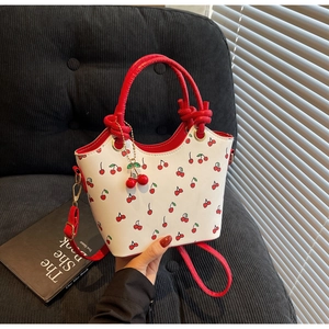 Détail du sac blanc à motifs cerises rouges avec poignées et pendentif cerise assortis