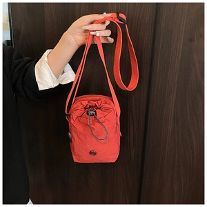 Close-up of orange waterproof nylon crossbody bag with drawstring closure and black strap