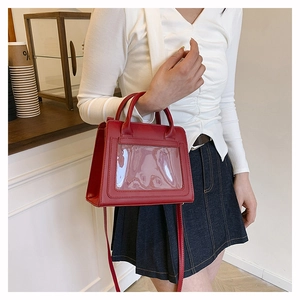 Détail d'un sac à main rouge vintage en cuir avec poche PVC transparente porté par femme