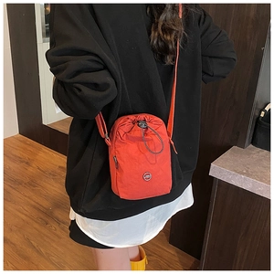 Detail of crossbody orange nylon bag featuring drawstring closure and JZD circular logo