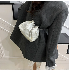 Detail of white satin bucket bag featuring butterfly embroidery and pearl chain