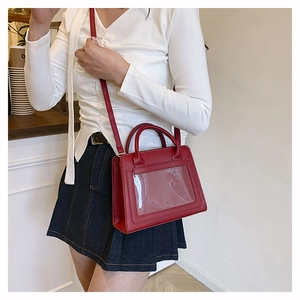Détail d'un sac à bandoulière en cuir rouge avec fenêtre porté à l'épaule d'un mannequin