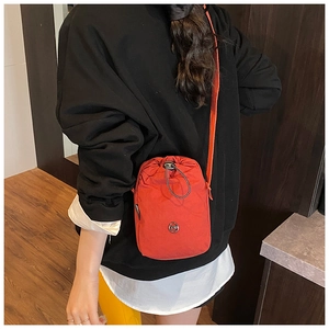 Detailed view of red nylon crossbody bag with drawstring closure and metal logo on model