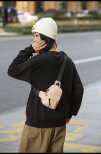 Detail of a lightweight beige nylon crossbody bag worn with casual streetwear outfit