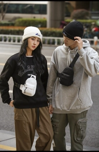 Street style view of couple wearing black and white nylon crossbody bags with adjustable straps
