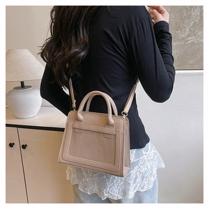 Détail d'un sac à main en cuir beige mat avec bandoulière réglable et poignées élégantes