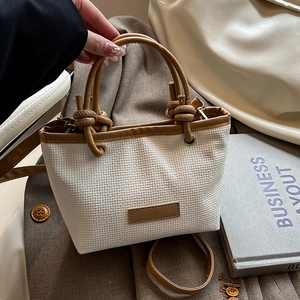 Handwoven straw bucket bag with brown leather handles and adjustable shoulder strap