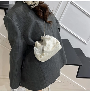 Detail view of cream bucket bag with floral embroidery and 3D butterfly on a model