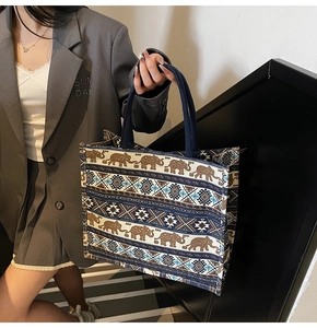 Detail of a large ethnic canvas tote bag with elephant patterns on a grey blazer outfit