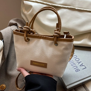 Stylish beige straw bucket bag with dark brown knot handle and matching shoulder strap