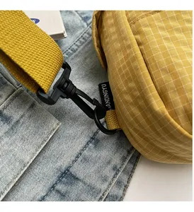 Detail of black plastic hook and yellow woven strap on a checkered canvas bag