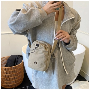 Khaki nylon crossbody bag with adjustable strap and circular logo on a lifestyle model