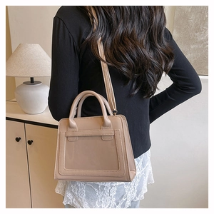 Minimalist beige crossbody bag shown on a shoulder in a modern interior setting