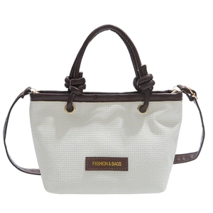 Minimalist white straw woven bucket bag with brown leather trim and knotted handle