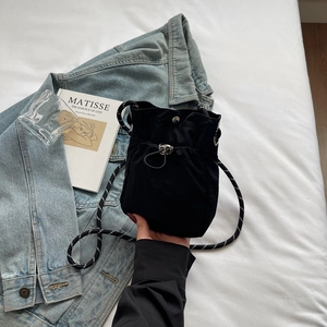 Detailed close-up of a black nylon drawstring bucket bag with woven rope shoulder strap