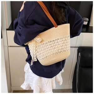 Detail of straw tote bag with white lace bow and brown shoulder strap on model