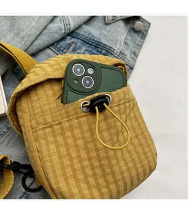 Detail of yellow checkered crossbody bag showing interior capacity for a mobile phone