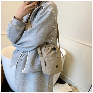 Macro detail of khaki water-resistant nylon crossbody bag with black drawstring closure
