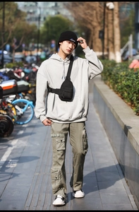 Close-up of olive green cargo pants with functional pockets and black nylon crossbody bag