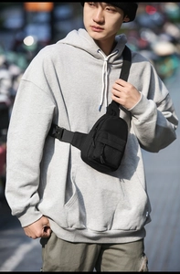 Close-up of black nylon crossbody bag with adjustable buckle strap and zip pocket