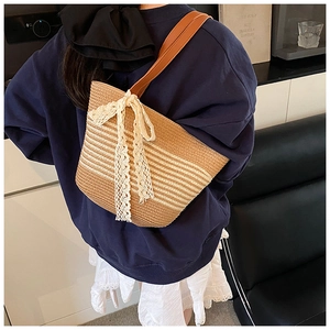 Detail showing woven texture of striped straw tote bag with elegant lace bow decoration