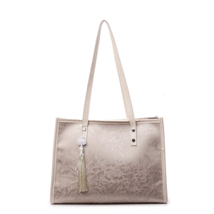 Large beige tote bag with leaf embossed pattern and white tassel charm on white background