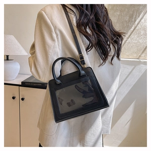 Détail d'un sac à main noir minimaliste avec fenêtre PVC transparente et boucles dorées