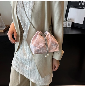 Detail of pink lace drawstring bucket bag with floral embroidery and pearl chain