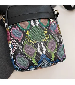 Detail of colorful snakeskin embossed pattern on small crossbody bag with silver zipper