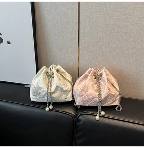 Detail of lace butterfly bucket bags with silver chain straps and pearl drawstring charms