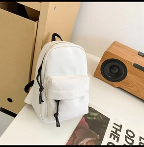 Detailed view of white canvas texture and black drawstring on a stylish mini backpack