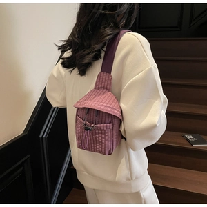 Detail of purple plaid crossbody bag with drawstring pocket worn over a white hoodie