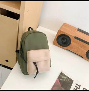 Top view of a mini canvas backpack with olive green and beige patchwork and drawstrings