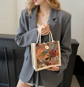 Detail der floralen Gobelin-Tasche mit Baumwollseilgriffen und einem großen weißen Knopf