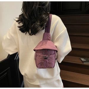Detail of purple plaid crossbody bag with wide strap and drawstring closure worn by model