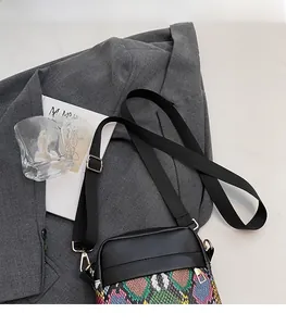 Detail of trendy crossbody bag with colorful snakeskin pattern on gray suit backdrop