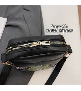 Close-up of golden zipper hardware on black leather bag with snake pattern detail